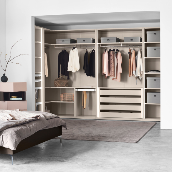Modernes Schlafzimmer mit begehbarem Kleiderschrank der Marke Kettnaker im Hintergrund.