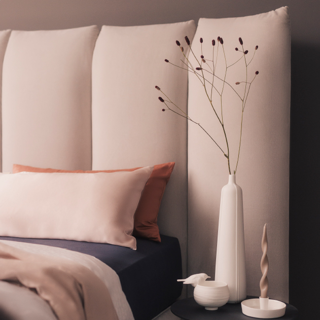 Boxspringbett der Marke SCHRAMM mit einem dekorierten Nachtisch daneben.