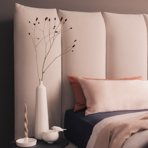 Boxspringbett der Marke SCHRAMM mit einem dekorierten Nachtisch daneben.