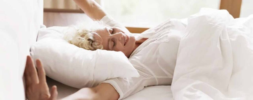 Frau liegt im Bett und regt sich.
